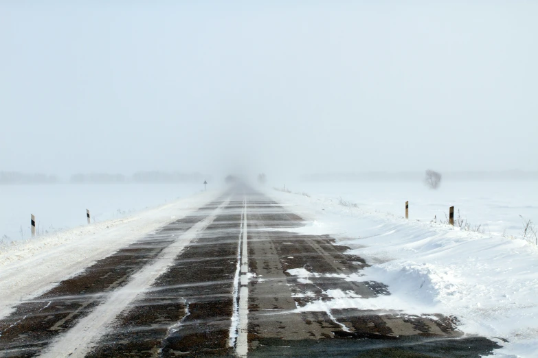 there is a bus driving along the snow road