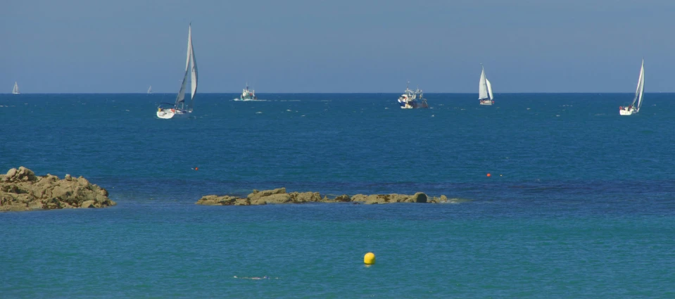 sailboats in the ocean off the rocks and sand