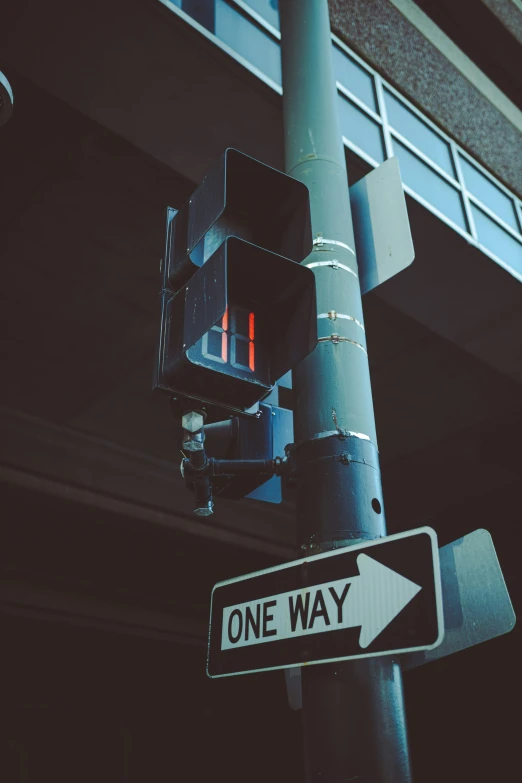 one way sign next to a street light under a bridge