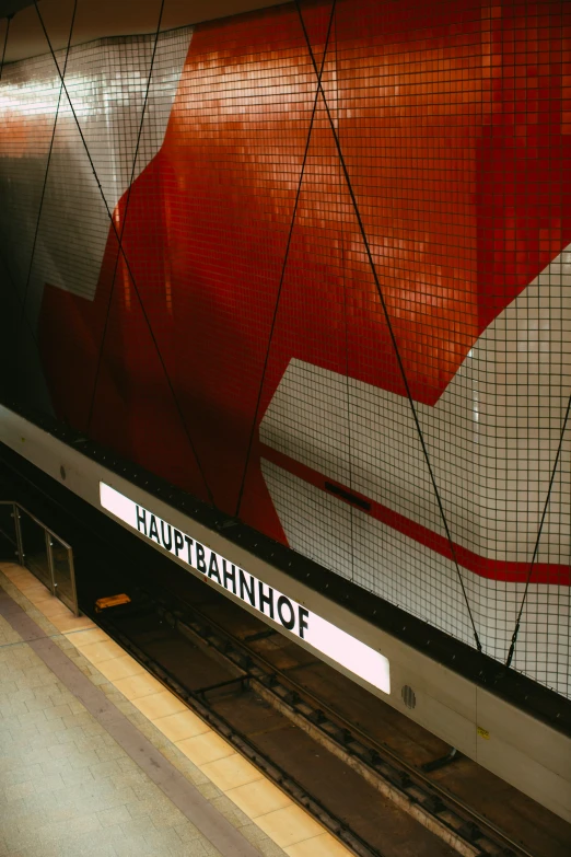 a red sign with words on it is mounted inside a subway