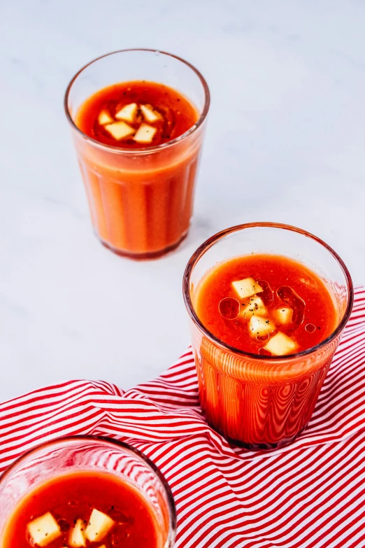 there are two glasses filled with a tomato soup