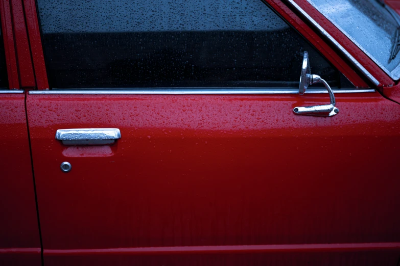 a red car door handle with water drops on it