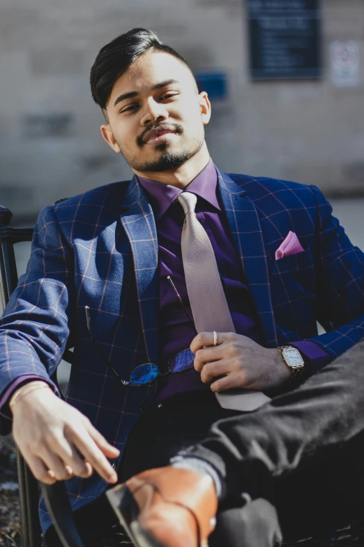 a man is sitting outside in a purple suit