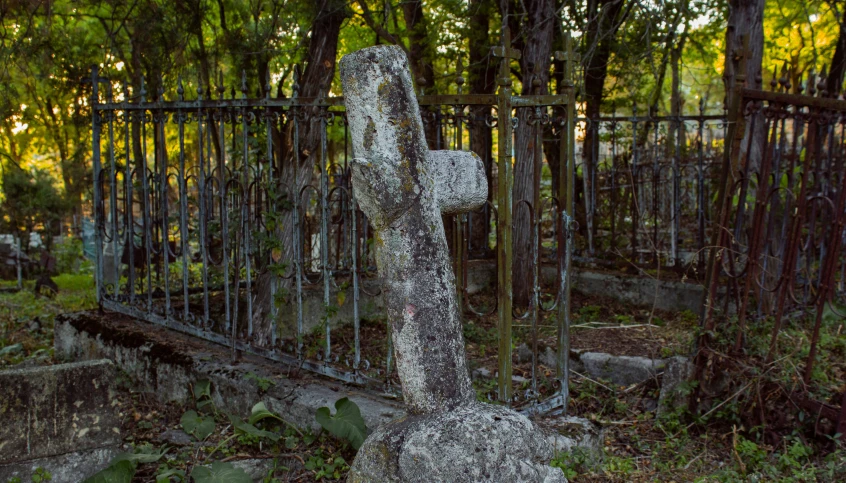 a stone cross with a iron fence around it