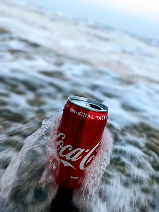 a can of coca - cola is frozen on the beach