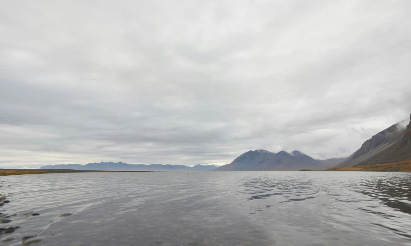 a river with calm water and mountains in the distance