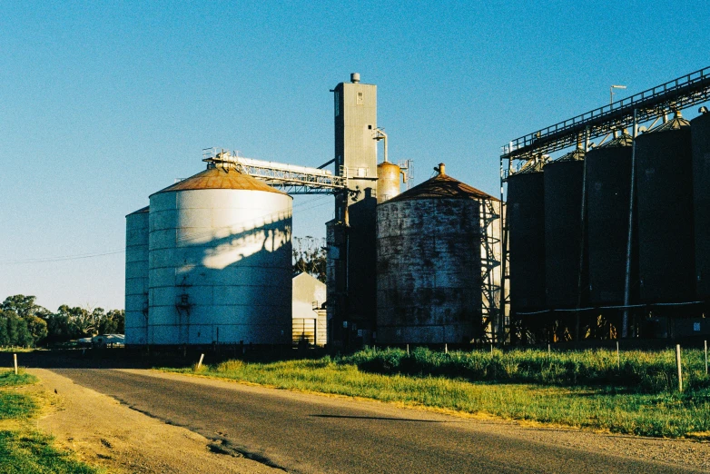 a country road next to some tall grain silos