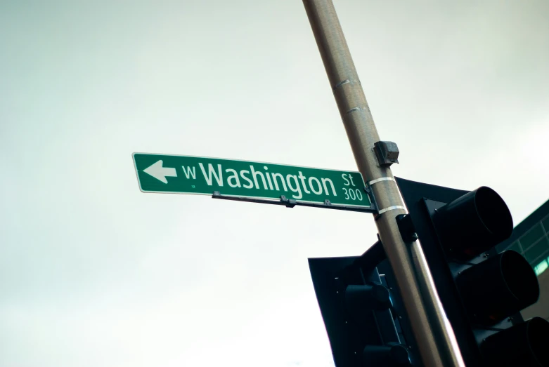 a green street sign hanging from a traffic light