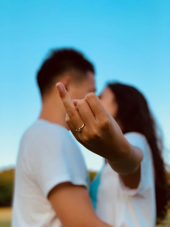 a woman standing next to a man as they give the peace sign