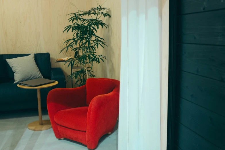 a red chair sitting by a black couch with pillows