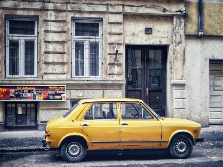 a small yellow car parked in front of a building