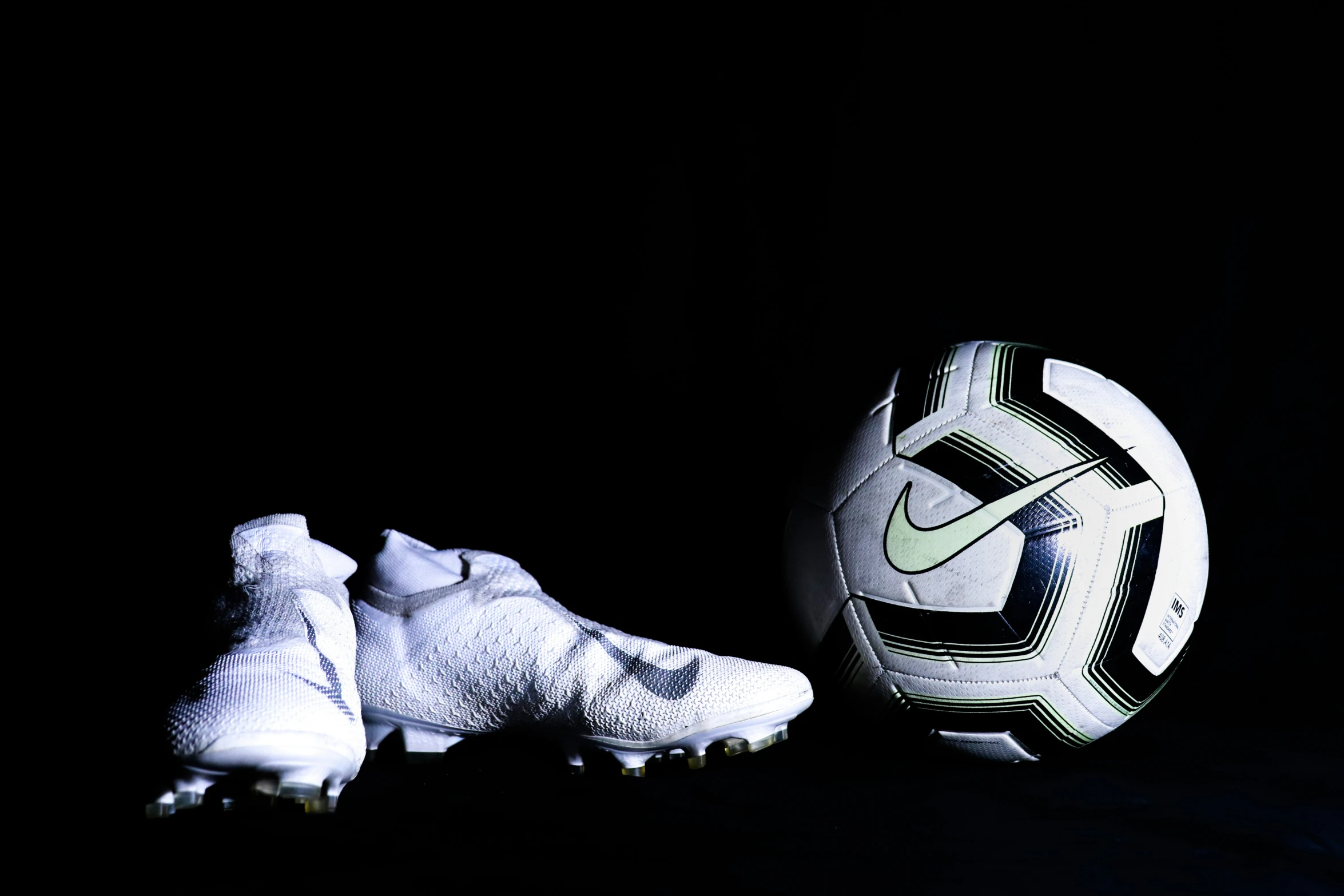a soccer ball and some shoes on a black background