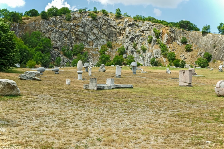 several stonehenges sitting in a field, with a rock formation behind them