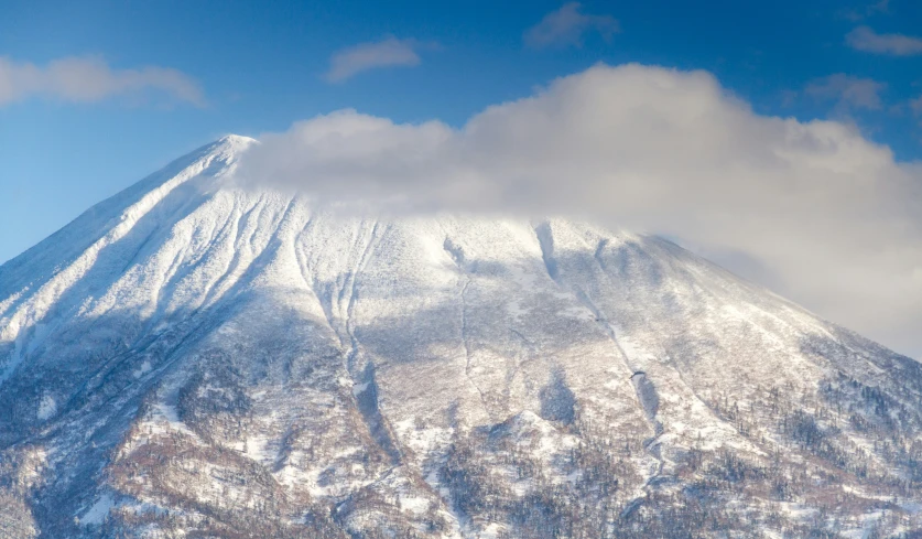 the top of a snow covered mountain with a blue sky behind it