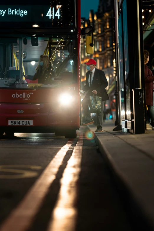 a red double deck bus with a man boarding it at night