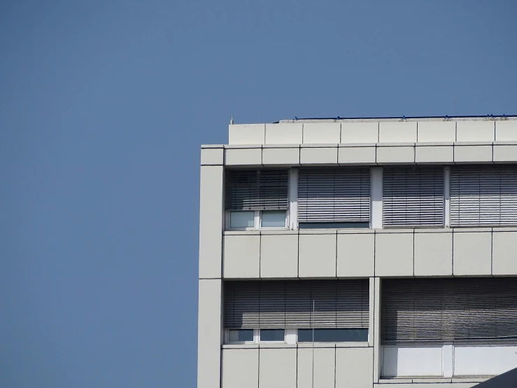 a grey building with windows and an airplane in the sky