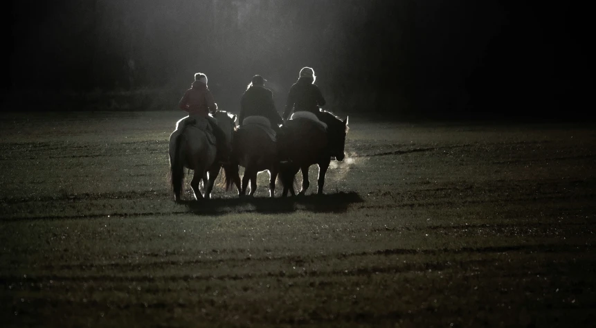 the riders are on horseback under the bright spotlight