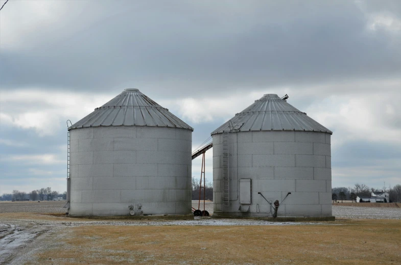 two silos sitting in an open field next to each other