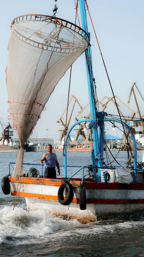 a man on the front of a boat holding onto a sail