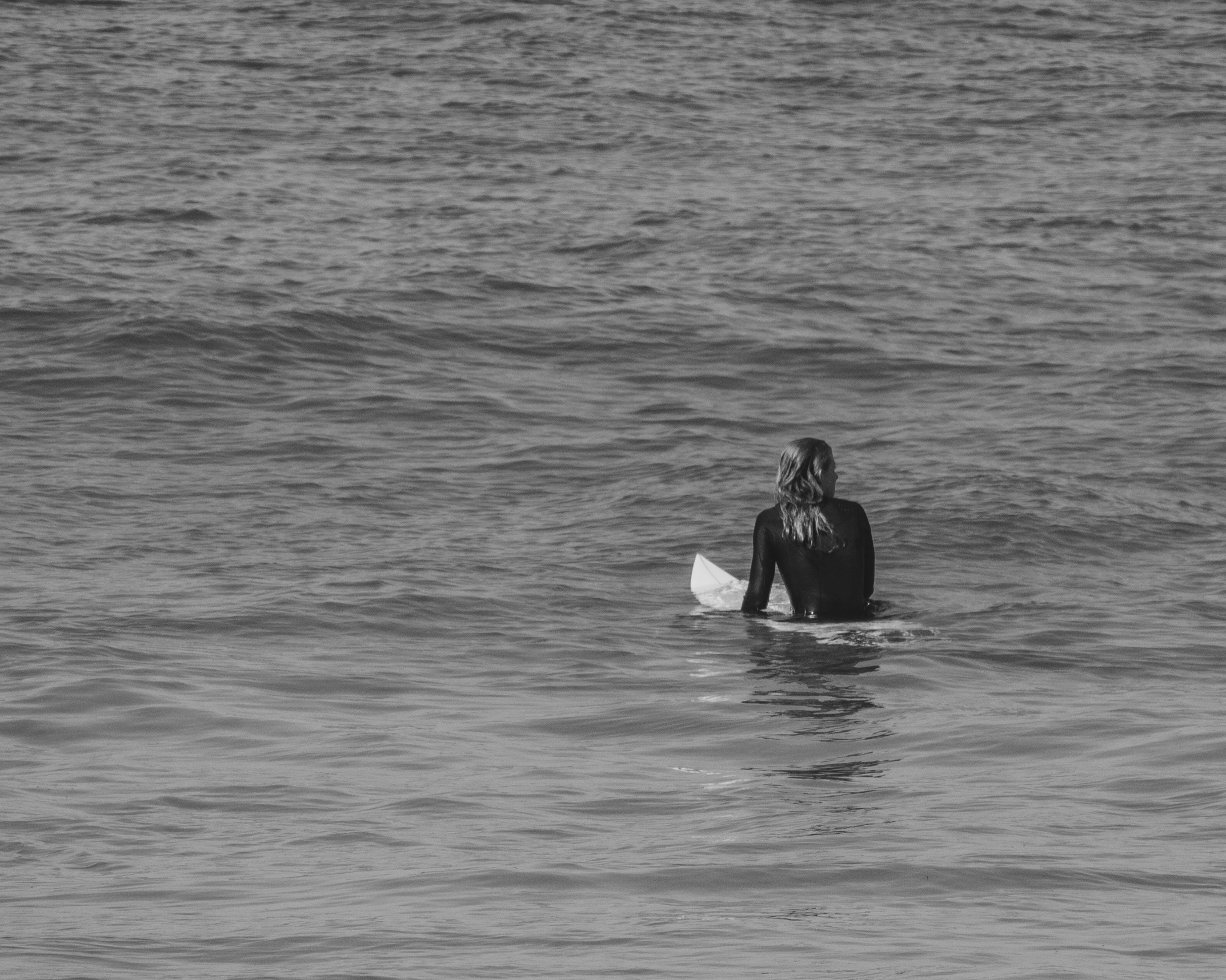 black and white pograph of a surfer riding out to sea