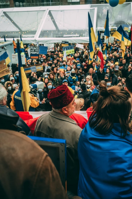 a large crowd gathered outside in winter, holding flags