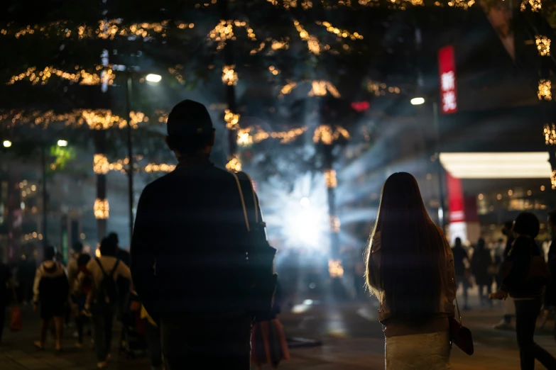 a couple is silhouetted against the night sky with lights at their sides