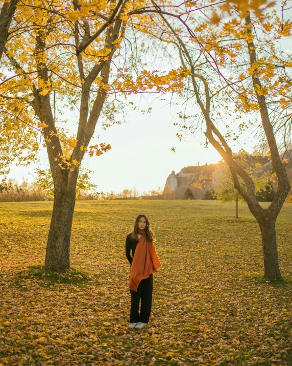 a woman standing next to three trees in a field