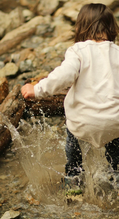 a child playing in the river holding a log