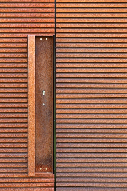 a brown door with an open window is behind a building that has vertical slats