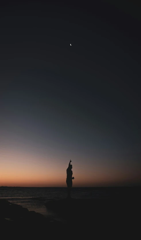 a man on the beach watching a small airplane fly overhead