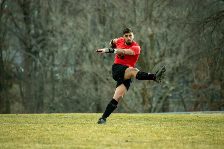 man with red uniform on playing soccer in field