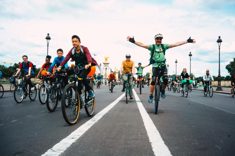 a group of bicyclists riding down the road with a lot of people watching