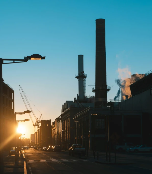 the sun is setting in the background of an industrial city