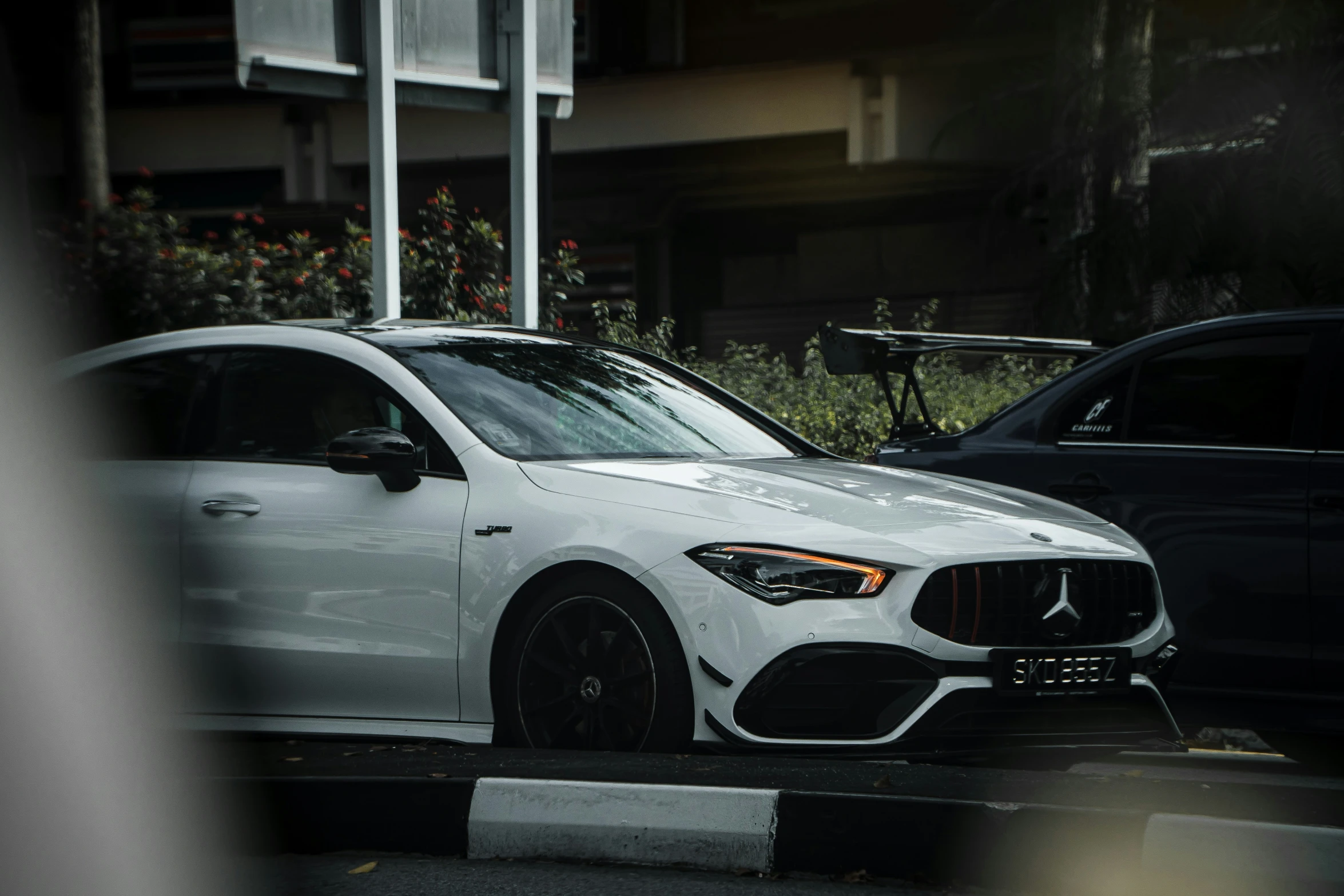 a white mercedes amg cla is parked beside a black bmw f9