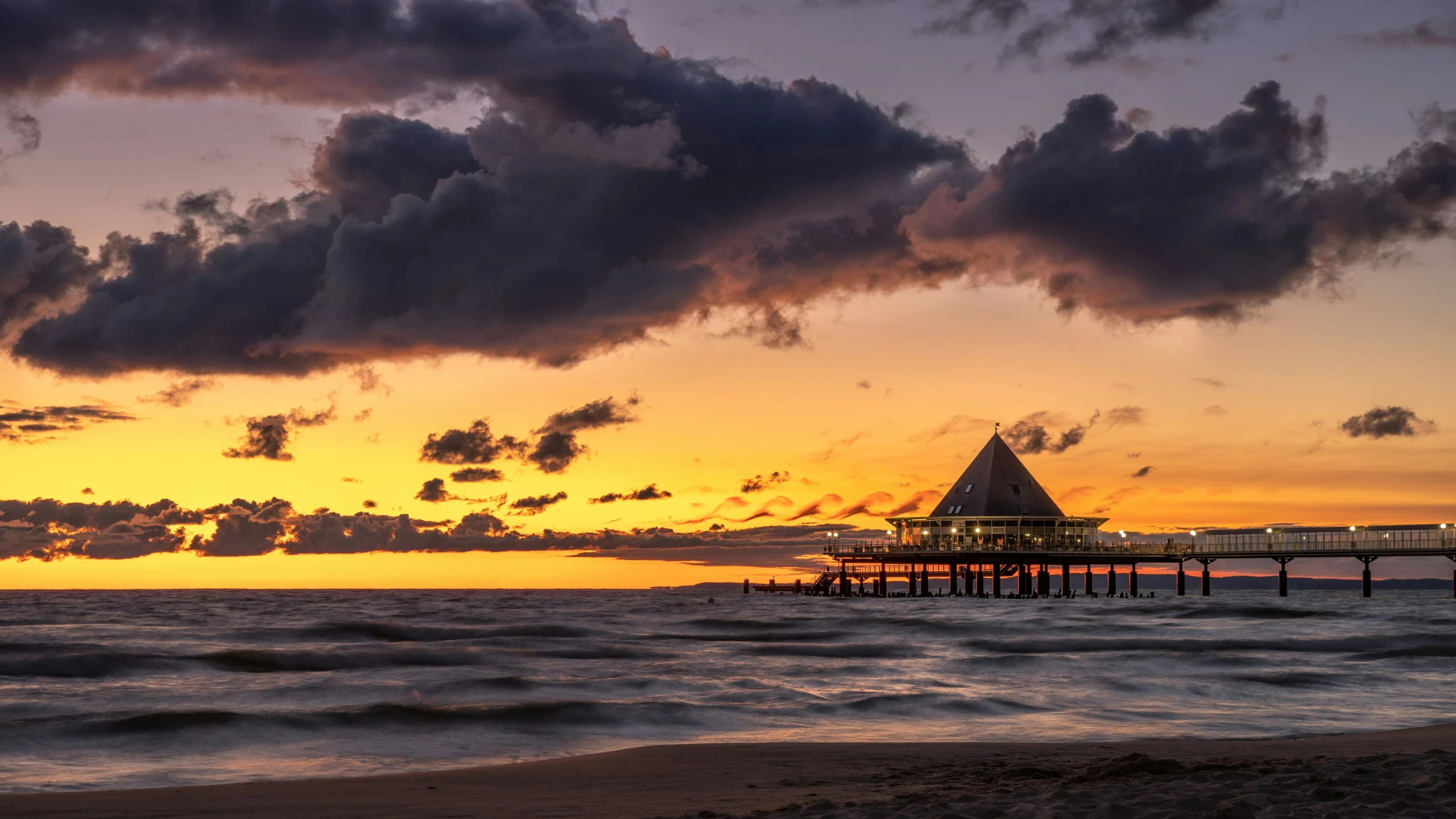 a sunset with clouds and boats on a pier