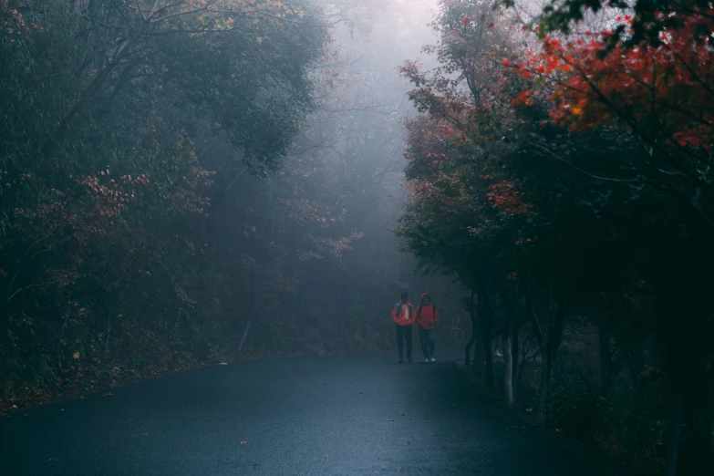 two people walking down the road in the rain