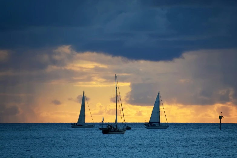 three boats on the ocean with cloudy skies