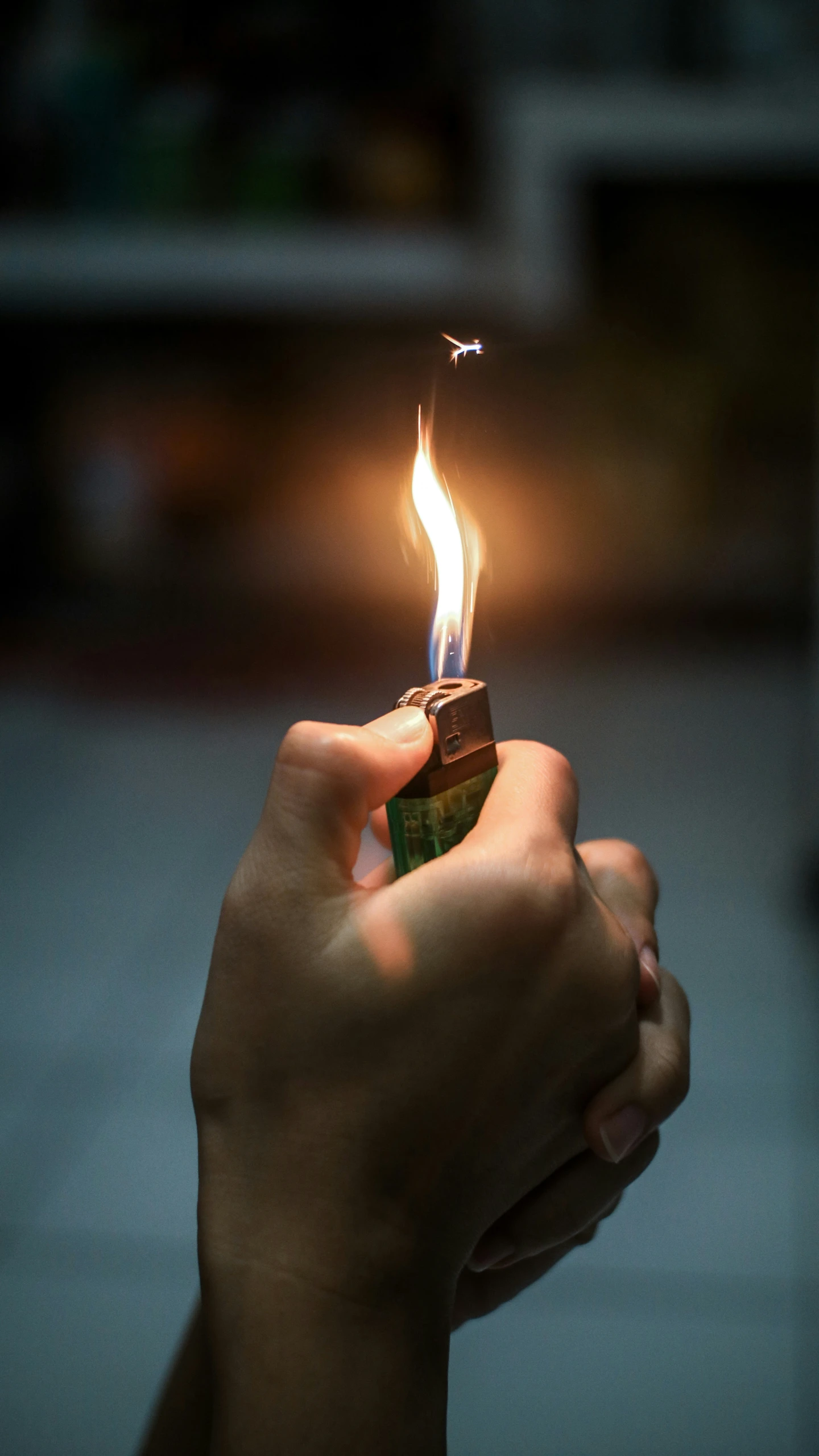 someone holding up a small lighter with their left hand