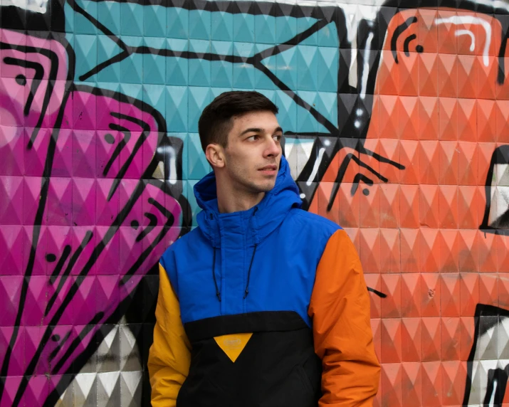 a man in front of a graffiti wall, his eyes are to the left