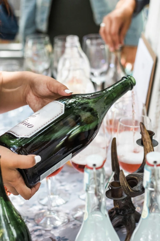 hands pouring champagne into bottles at an event