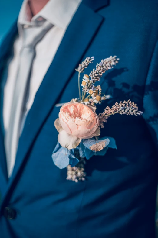 a man in a blue suit and flower boutonniere