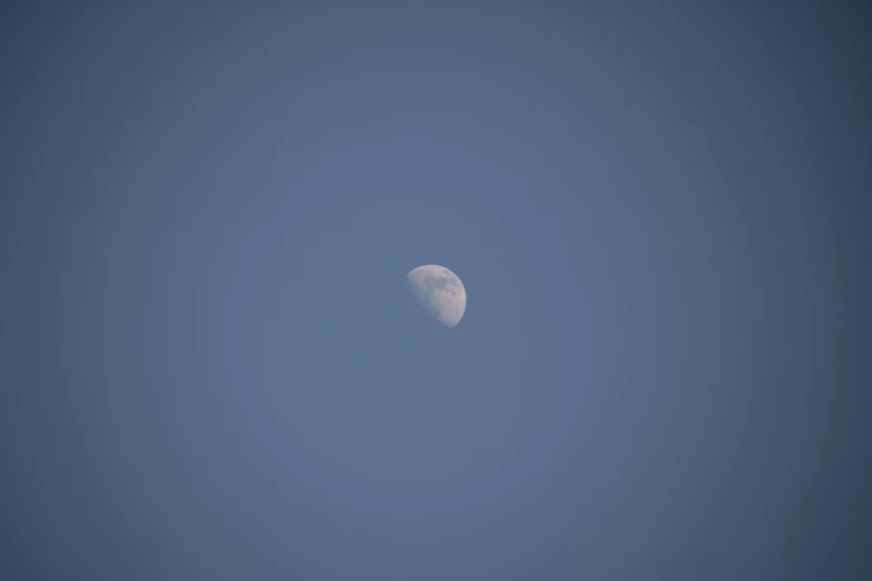 the moon is seen through the dark blue sky