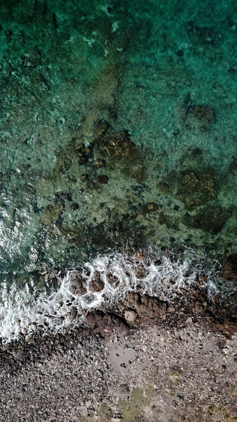 the view from above of a beach with surf and water