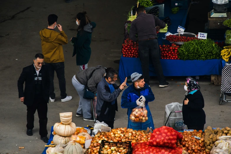 two children at an outdoor produce market and a man on the phone