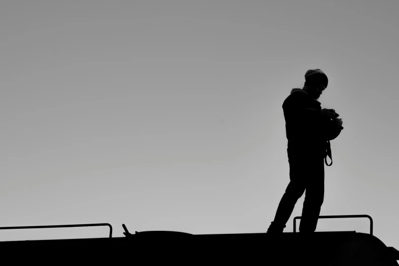 the silhouette of a man standing on a roof