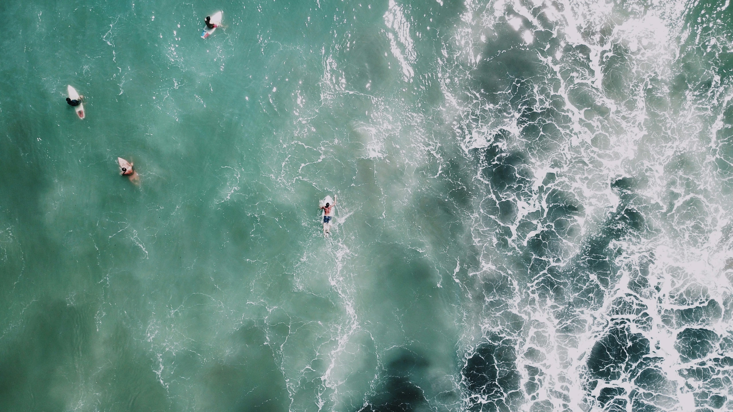 people are swimming in the waves of a beach