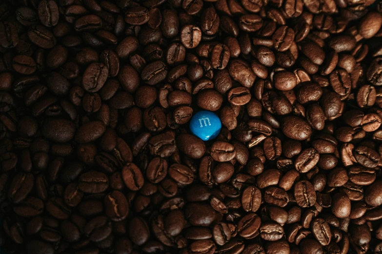 blue ball surrounded by coffee beans on black ground