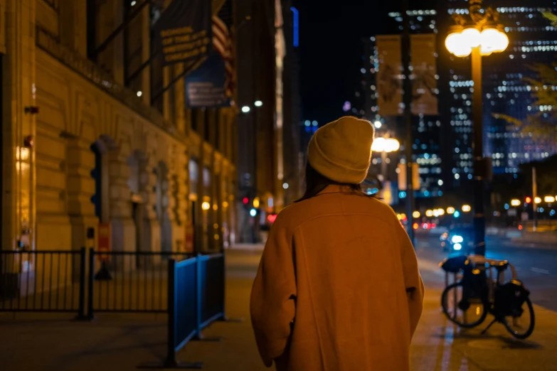 a woman in brown coat standing on street next to a sidewalk