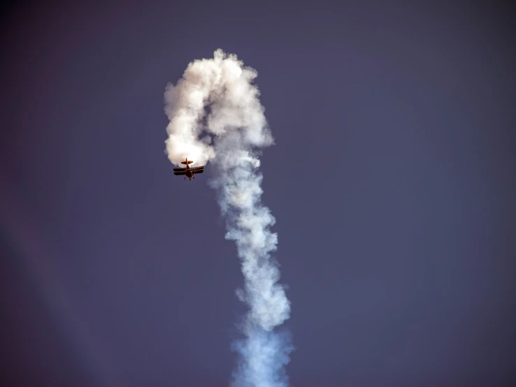 smoke billows from the top of a stunt plane