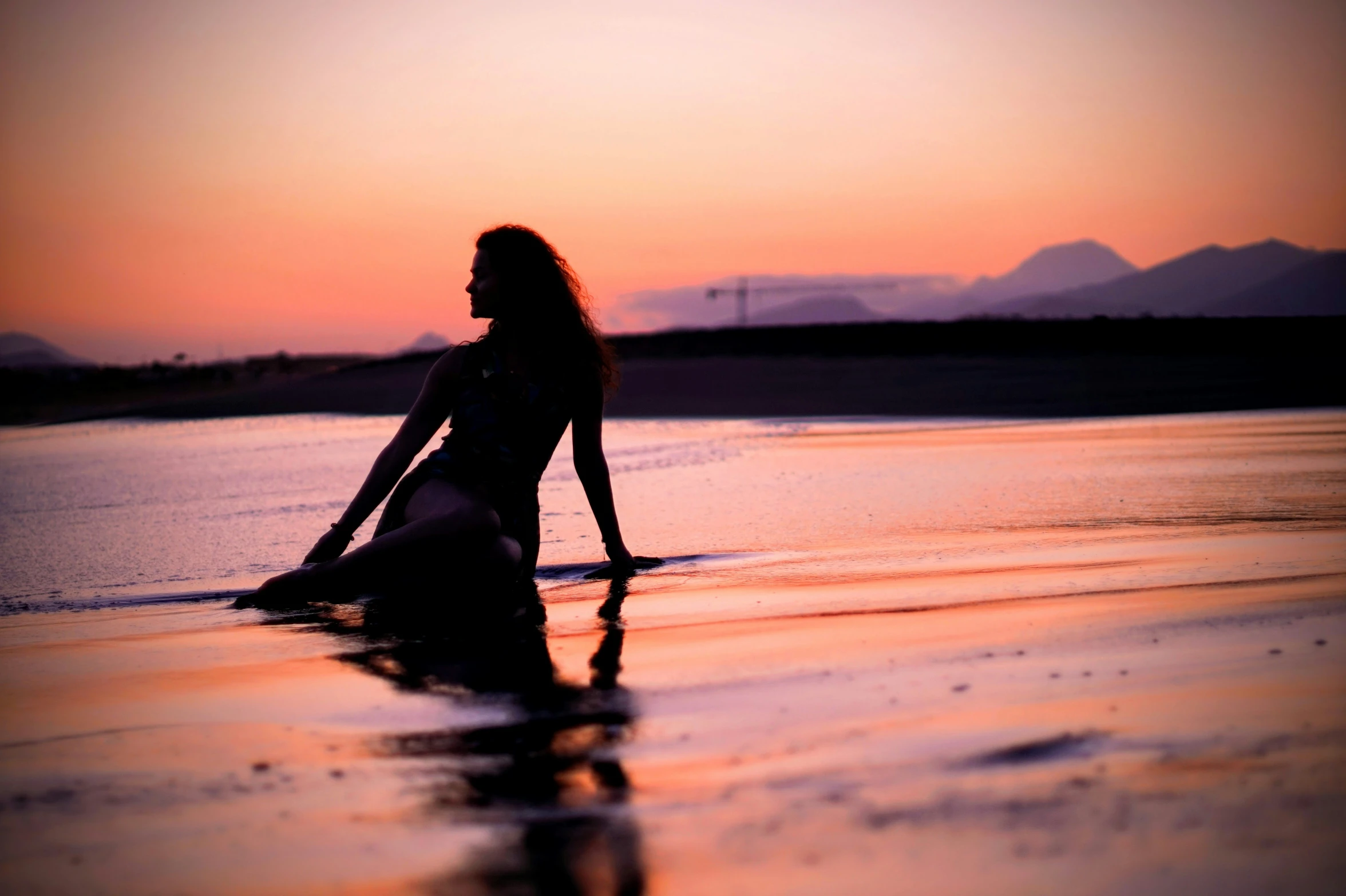 a woman in the water at sunset with her surfboard